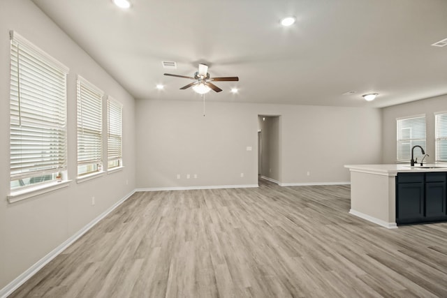 18798 Lucas Michael Way, New Caney, TX 77357 - unfurnished living room with a ceiling fan, light wood-style flooring, recessed lighting, baseboards, and a sink