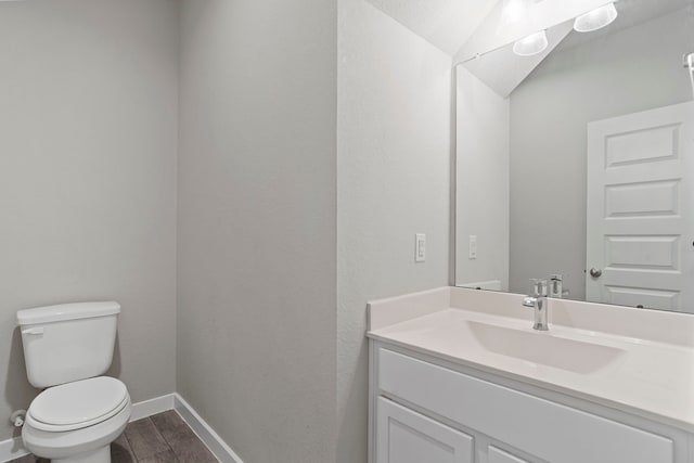 bathroom featuring toilet, vanity, baseboards, and wood finished floors