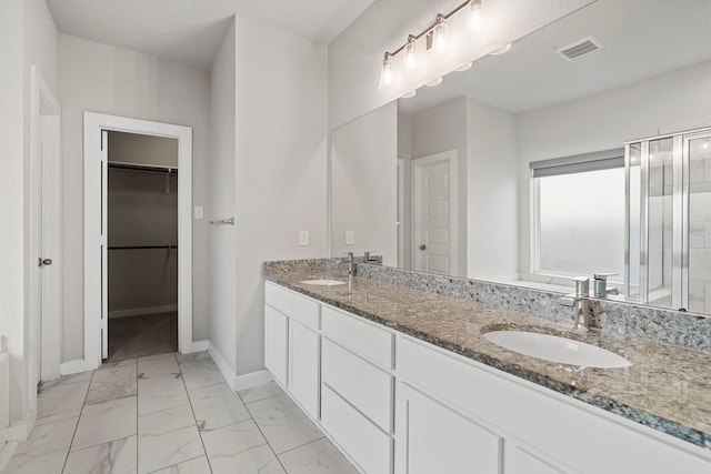 full bathroom with marble finish floor, a sink, a walk in closet, and baseboards