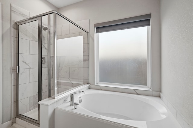 full bathroom featuring a textured wall, a stall shower, and a bath