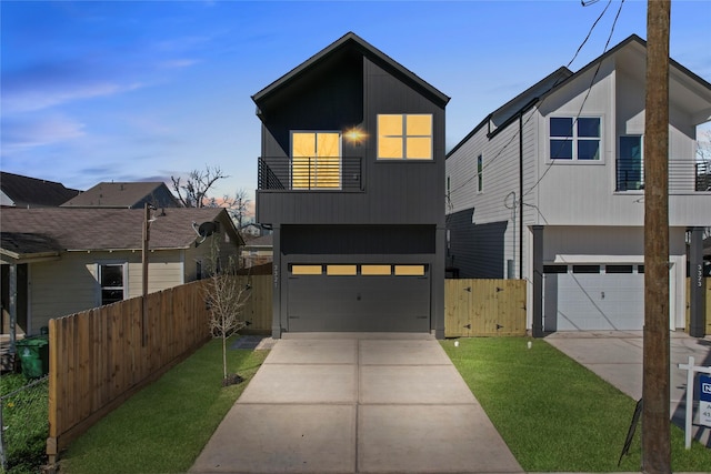 modern home featuring a gate, fence, concrete driveway, a garage, and a balcony