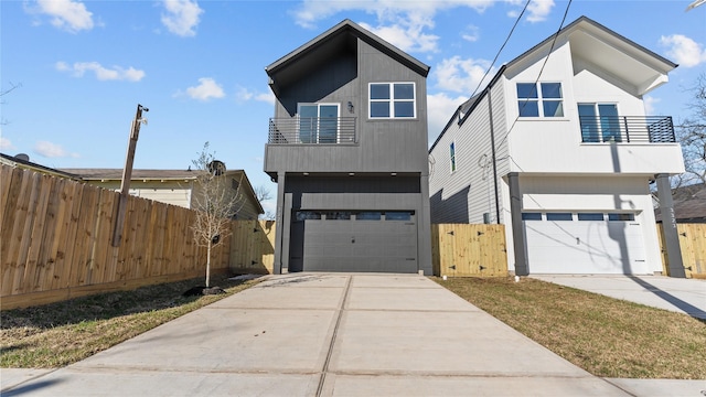 view of front of house with an attached garage, fence, a balcony, driveway, and a gate