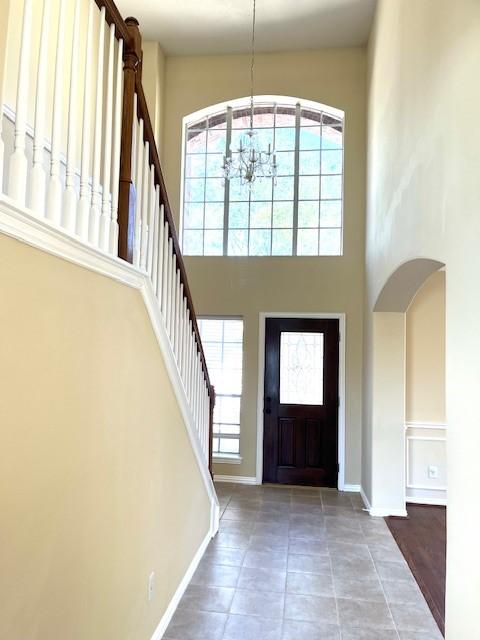 entrance foyer with baseboards, a high ceiling, stairway, and an inviting chandelier