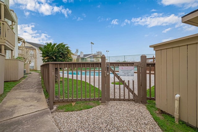 view of gate with fence and a community pool