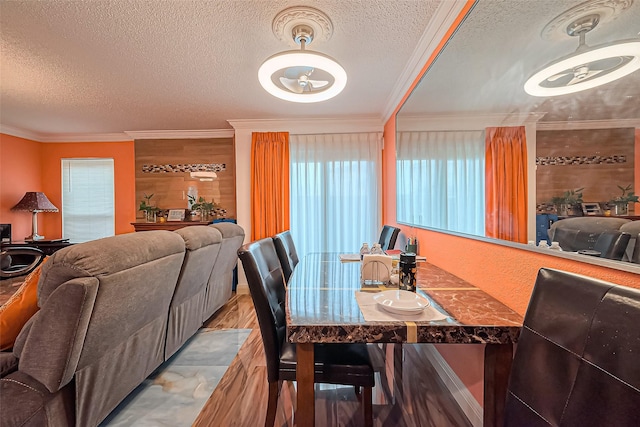 dining space with a textured ceiling, wood finished floors, and crown molding