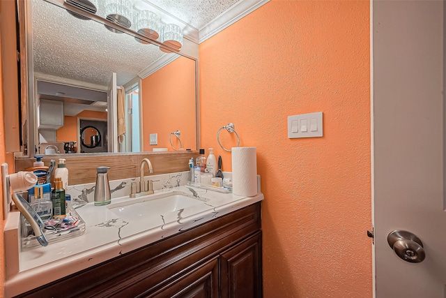 bathroom with a textured ceiling, a textured wall, vanity, and crown molding