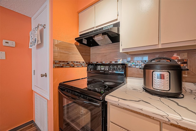 kitchen featuring under cabinet range hood, visible vents, white cabinets, black electric range, and tasteful backsplash