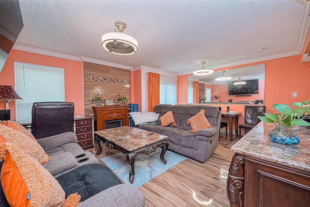 living area with a textured ceiling, ornamental molding, and light wood-style floors