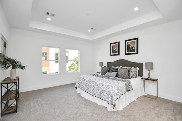 bedroom featuring baseboards, visible vents, and a tray ceiling