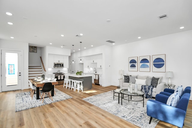 living area featuring light wood-style flooring, stairway, visible vents, and recessed lighting