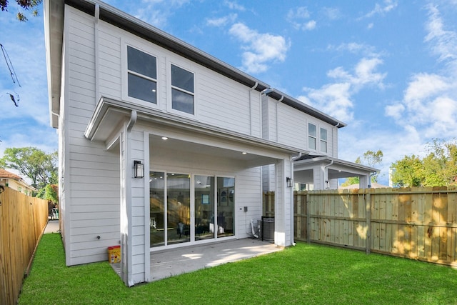 rear view of house featuring a patio, a lawn, and a fenced backyard