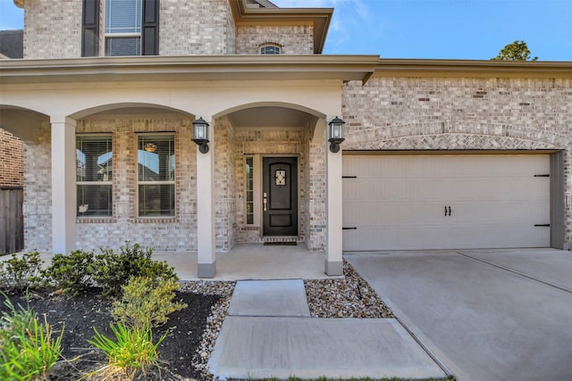 property entrance with a porch, brick siding, driveway, and an attached garage