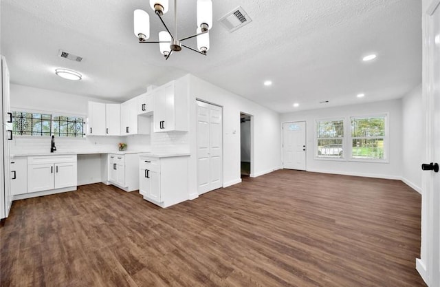 kitchen with dark wood-style floors, open floor plan, visible vents, and tasteful backsplash