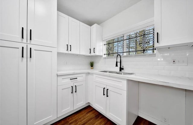 kitchen featuring tasteful backsplash, a sink, white cabinets, and light stone countertops