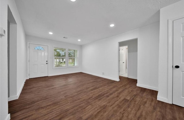 interior space with a textured ceiling, dark wood-style flooring, recessed lighting, and baseboards