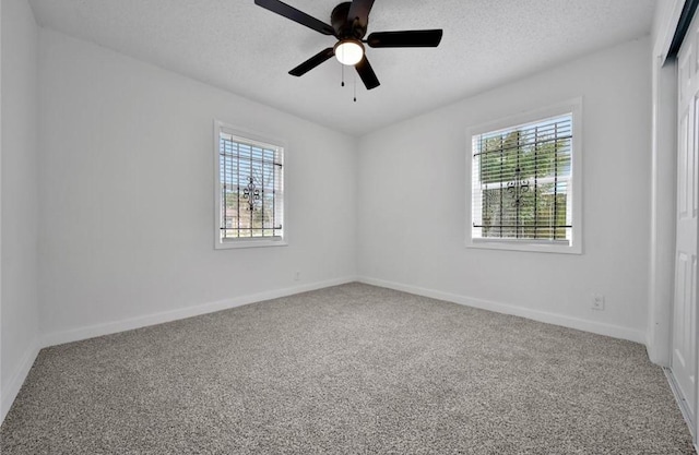 carpeted empty room featuring a textured ceiling, ceiling fan, and baseboards