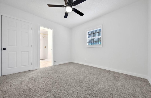 unfurnished bedroom featuring carpet, ceiling fan, a textured ceiling, and baseboards