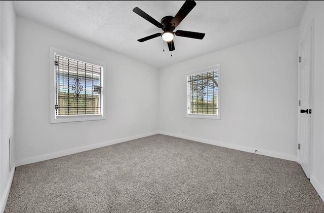 spare room with a textured ceiling, carpet flooring, a ceiling fan, and baseboards