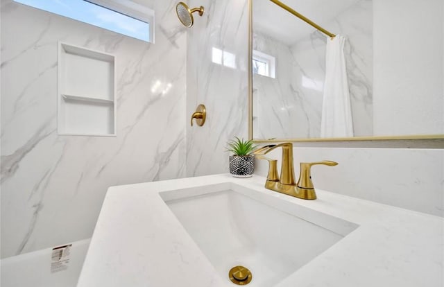 full bathroom featuring a sink and a marble finish shower