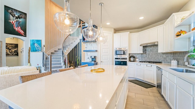 kitchen featuring tasteful backsplash, stainless steel appliances, under cabinet range hood, open shelves, and a sink