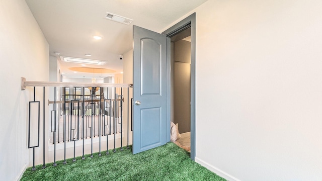 hallway with carpet, visible vents, and baseboards