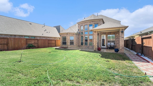 back of house featuring brick siding, a lawn, a patio area, and a fenced backyard