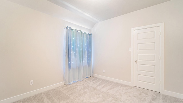 empty room featuring light carpet and baseboards