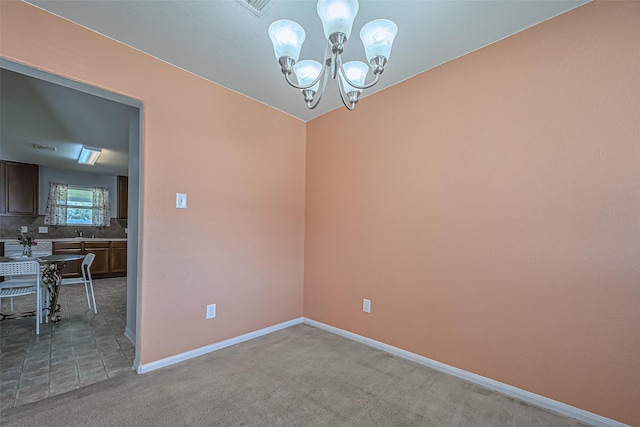 spare room featuring baseboards, a notable chandelier, and light colored carpet