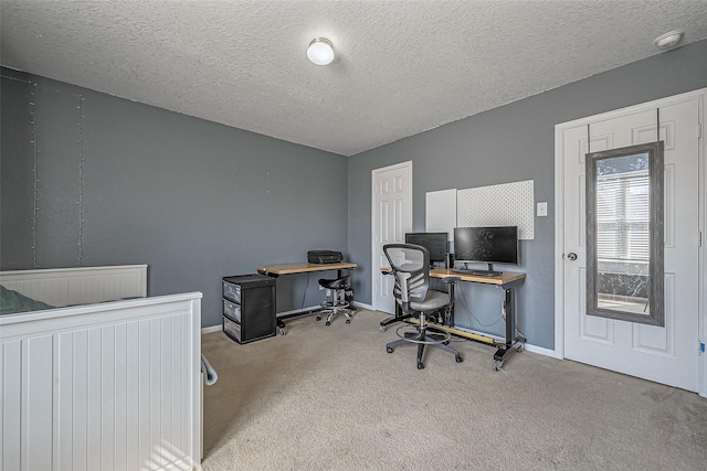 carpeted home office with a textured ceiling and baseboards