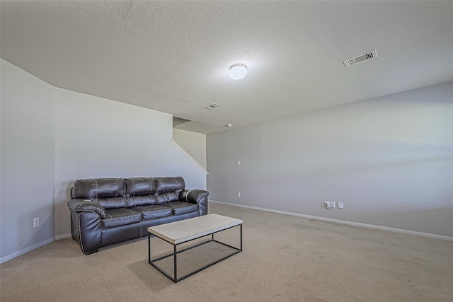 living room featuring visible vents, light carpet, and a textured ceiling