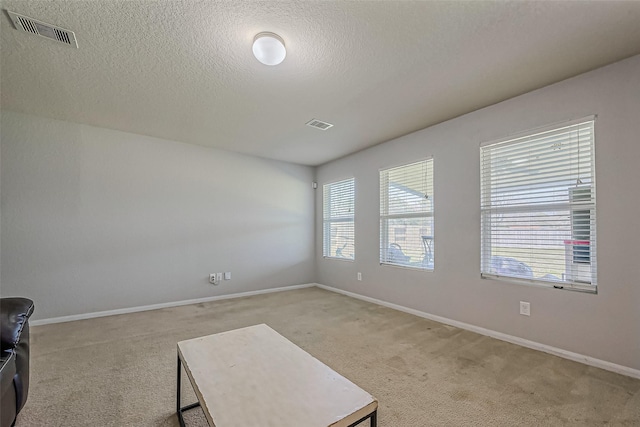 spare room featuring light colored carpet, visible vents, and baseboards