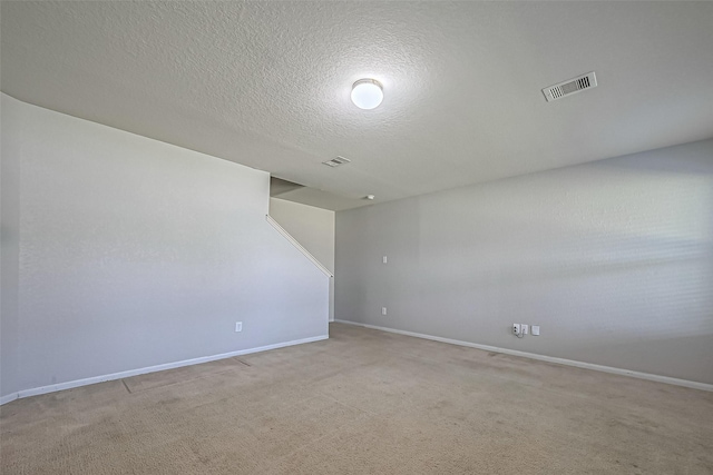 unfurnished room featuring a textured ceiling, baseboards, visible vents, and light colored carpet