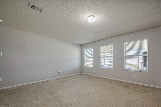 empty room with baseboards, visible vents, and light colored carpet