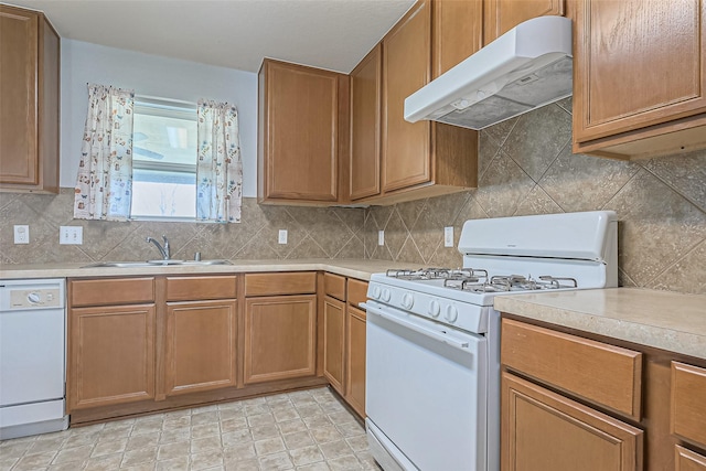 kitchen with under cabinet range hood, white appliances, a sink, light countertops, and decorative backsplash