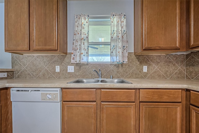 kitchen with light countertops, white dishwasher, and a sink