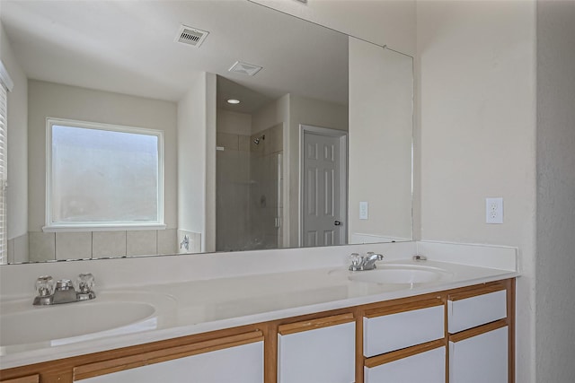 full bath with double vanity, visible vents, a sink, and walk in shower