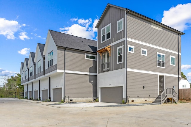 rear view of property with a garage, driveway, crawl space, and board and batten siding