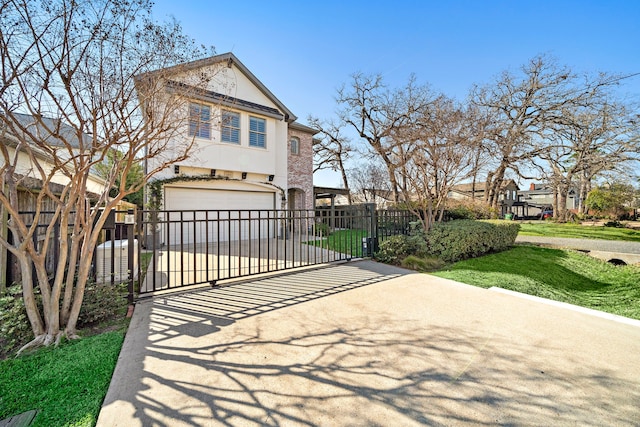 traditional home featuring stucco siding, driveway, a gate, fence, and brick siding