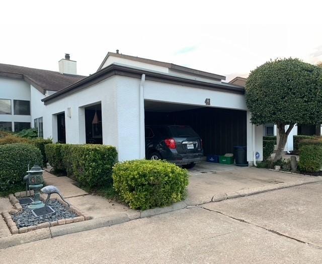 view of side of property featuring concrete driveway, an attached garage, and stucco siding