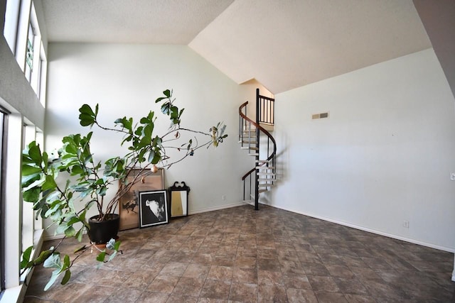 empty room featuring visible vents, baseboards, vaulted ceiling, stairway, and stone finish floor