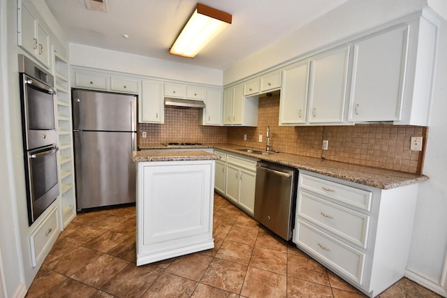 kitchen featuring appliances with stainless steel finishes, a kitchen island, a sink, and tasteful backsplash