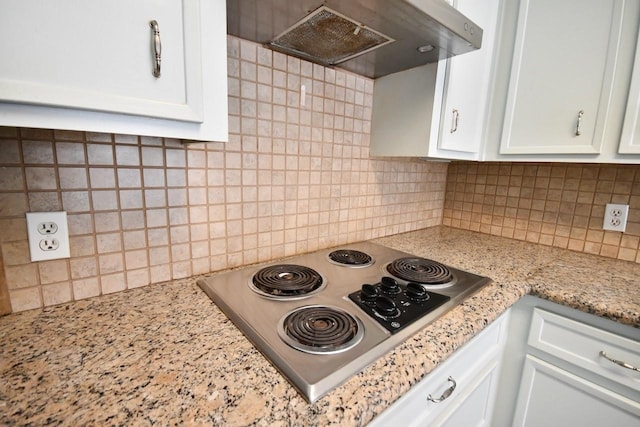 kitchen with light stone counters, backsplash, stainless steel electric cooktop, white cabinetry, and under cabinet range hood