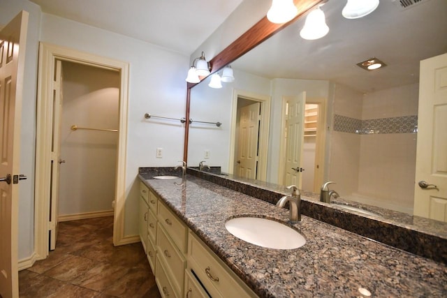 bathroom featuring a shower, a sink, and double vanity