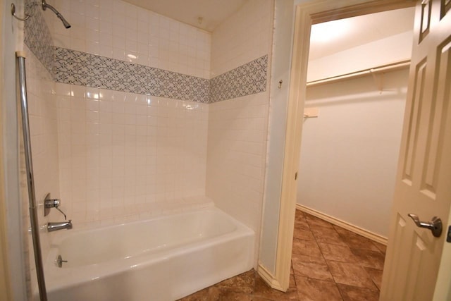 bathroom featuring baseboards, a walk in closet, and shower / bathing tub combination