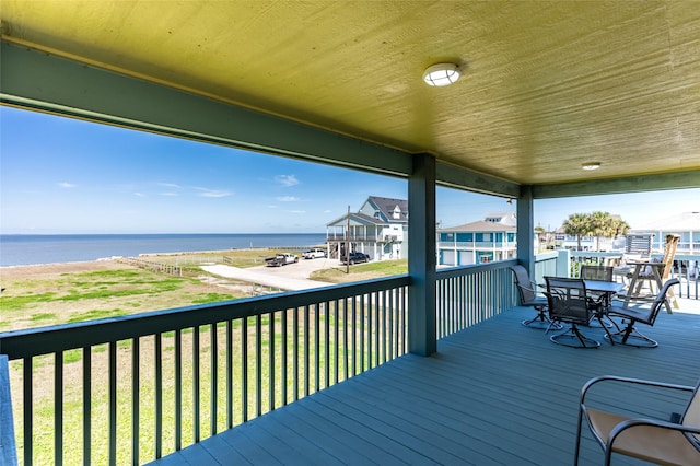 deck with outdoor dining area and a water view