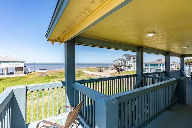 wooden terrace featuring a water view and a yard