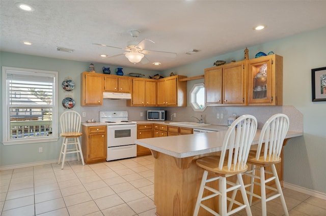 kitchen with electric stove, light countertops, stainless steel microwave, visible vents, and under cabinet range hood