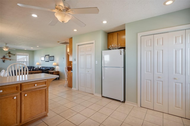 kitchen featuring brown cabinets, recessed lighting, freestanding refrigerator, open floor plan, and light tile patterned flooring