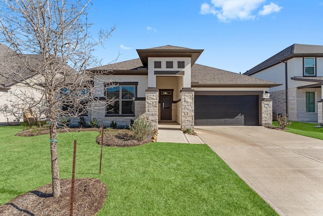 prairie-style home with a garage, driveway, stone siding, roof with shingles, and a front yard