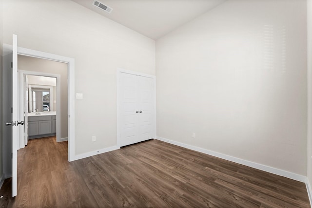 unfurnished bedroom with high vaulted ceiling, dark wood-style flooring, visible vents, baseboards, and a closet